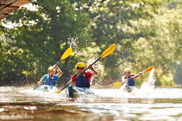 Eine Gruppe von Kanufahrern paddelt auf einem Fluss in der nähe von Bodenmais